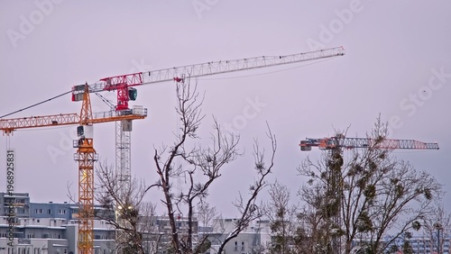 Tall Industrial Tower Crane Jib Arms at Skyscraper Construction Site above City Skyline