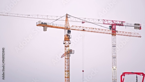 Tall Industrial Tower Crane Jib Arms at Skyscraper Construction Site above City Skyline