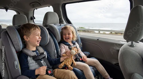 Obraz  z motywem Happy boy and girl sitting in child car seat during family road trip. Children secured in vehicle restraint system for travel safety. Automotive transportation and parenting concept.