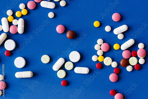 Pharmaceutical drugs on a blue background. Treatment with tablets and capsules. Multicolored and of different sizes