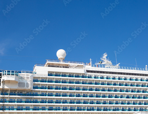 Luxury cruise ship deck with multiple balconies under clear blue sky, travel and vacation concept with copy space. Background