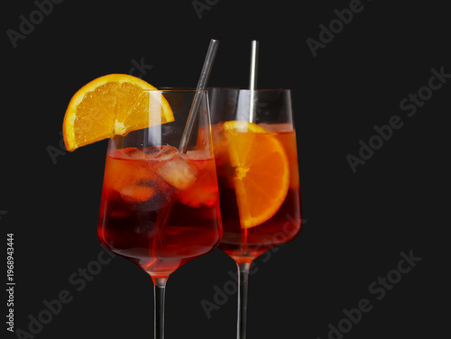 Two Aperol spritz cocktails with orange slice and ice.