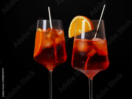 Two Aperol spritz cocktails with orange slice and ice.