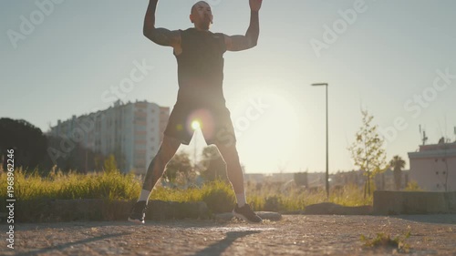 Tattooed athlete man doing jumping jacks outdoor workout