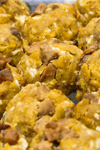 Close-up of Ecuadorian bolón mixto made of green plantain with cheese and pork cracklings in glass dish, ready to heat, traditional food”