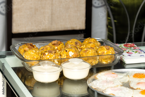 Ecuadorian bolón mixto made of green plantain with cheese and pork cracklings in glass dish, ready to heat, traditional food”