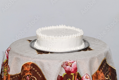 Minimalist white cake on table with motion blurred hands creating abstract dynamic effect in soft light setting