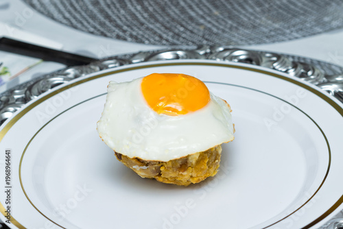 Close-up of Ecuadorian bolón mixto with fried egg on white plate, traditional Latin breakfast dish