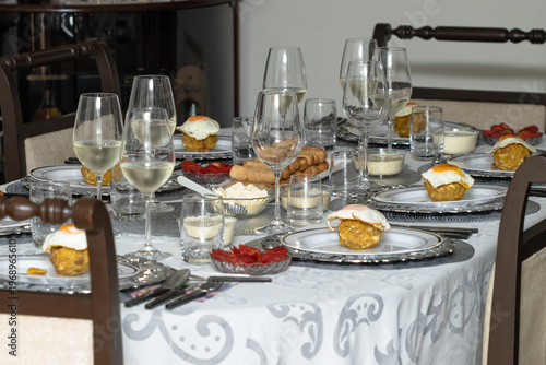 Elegant brunch table with traditional Latin American dishes, bolones with fried egg, wine glasses and assorted food spread