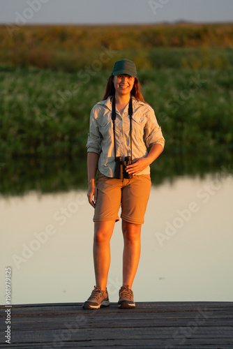 Woman birdwatching with binoculars at sunset outdoors