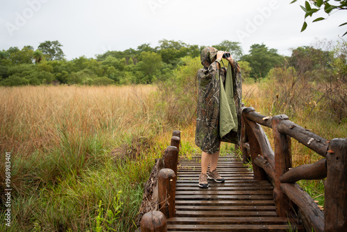 Person birdwatching with binoculars in swamp landscape