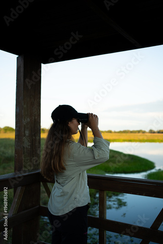 Woman observing nature with binoculars from birdwatching tower
