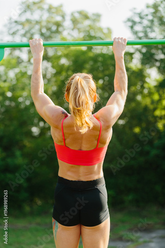 Woman exercising pulling up on outdoor bar