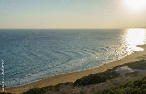 A tranquil sunset over a serene beach with gentle waves lapping at the golden shoreline.