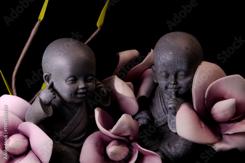 Zen monk statues with flowers close up on dark background meditation and mindfulness concept