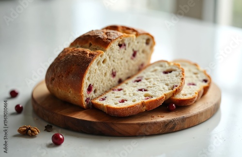 Sourdough bread loaf with cranberries and walnuts sliced on wooden board. Baked artisan pastry with red berries and nuts. Homemade bread for breakfast, cafe menu.