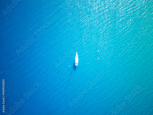White sailboat in crystal clear blue water