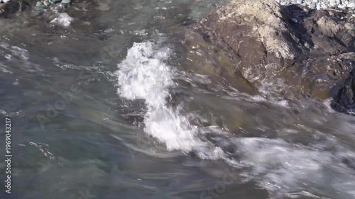Rapid river water hitting rocks and splashing in a mountain stream