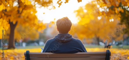 A person sitting on a bench in a vibrant autumn park.