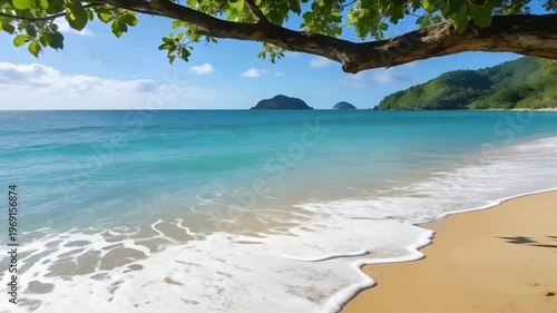 Serene Tropical Beach With Turquoise Waves Rolling Onto Golden Sand And Lush Island Background Under Clear Blue Sky