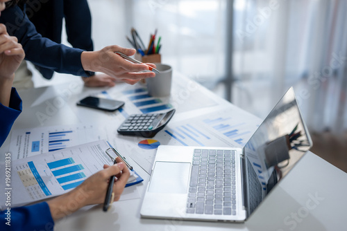 Business professionals analyzing financial data using laptop at office