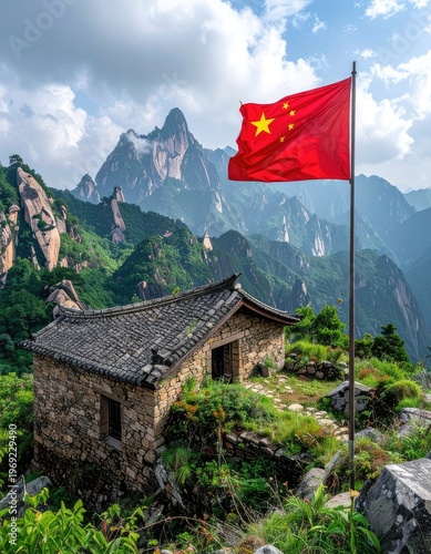 A small stone hut sits nestled amidst a dramatic mountain landscape in China, proudly displaying the national flag against a backdrop of towering peaks and a cloudy sky.