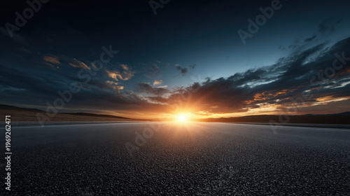 Sunset horizon over empty road with dramatic sky and glowing light on dark asphalt landscape