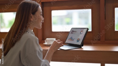 A woman is sitting at a table with a laptop and a cup of coffee. She is typing on the laptop and she is focused on her work. Concept of productivity and concentration