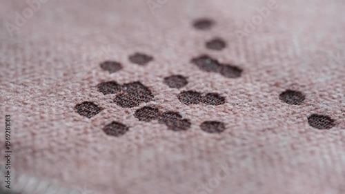 Close up a candle dripping wax onto cloth, creating spots and patterns pink background at a cozy location. Concept of everyday life problem and home cleaning. 