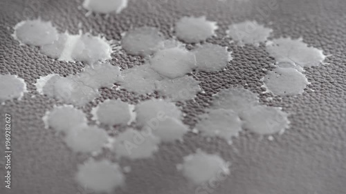 A candle dripping wax leather furniture, creating spots and patterns gray background at a cozy location. Concept of everyday life problem and home cleaning