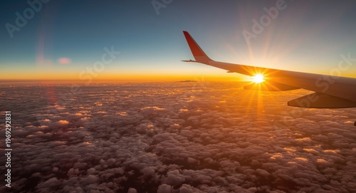 Sunset panorama from airplane wing above cottony clouds showcasing lens flare