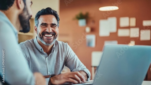 Two colleagues collaborating on a laptop in a modern office space