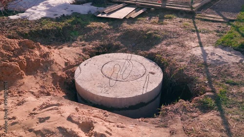 Wallpaper Mural Concrete ring water storage tank with manhole cover buried in ground close-up Torontodigital.ca
