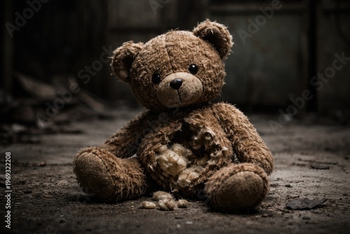 Abandoned teddy bear with torn tummy resting on a cold hard surface