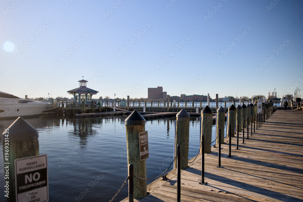 Obraz premium Wooden marina pier with calm water under clear daylight sky