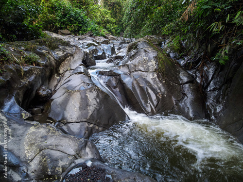 Картината върху платно Aerial view of Waterfall cascading over smooth stones in a tropical jungle, Clea
