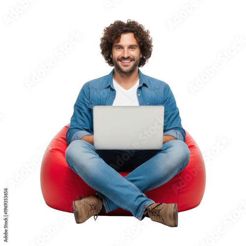 A young man sitting comfortably on a red bean bag with a laptop