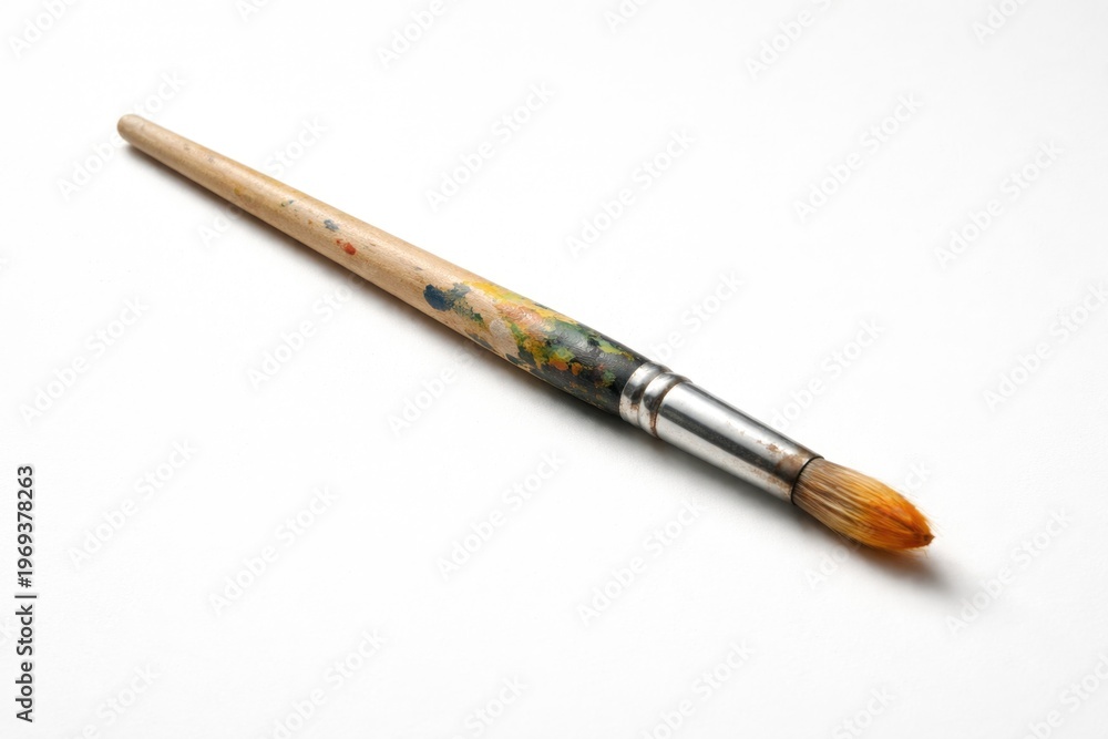 Naklejka premium paintbrush resting on a plain white backdrop with soft shadows