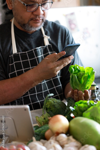 Middle Aged Asian Man Using Smartphone to Choose Healthy Food at Home