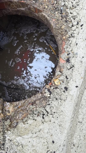 Reflective Oily Water In Drain Cavity Shimmering Surface Reveals Contamination And Trapped Leaf Litter, Gritty Concrete Rim With Sediment, Urban Runoff Hazard, Environmental Concern