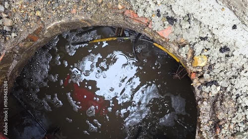 Reflective Oily Water In Drain Cavity Shimmering Surface Reveals Contamination And Trapped Leaf Litter, Gritty Concrete Rim With Sediment, Urban Runoff Hazard, Environmental Concern