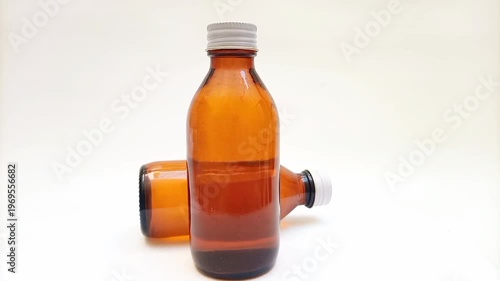 Amber glass bottles with cap rotating on white background, brown glass bottles for pharmaceuticals, syrups, essential oils, and cosmetics