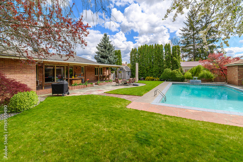 Fotografi A landscaped back yard with covered deck, patio, and swimming pool in a mid-century modern home with brick exterior in the  suburban Pacific Northwest of the United States
