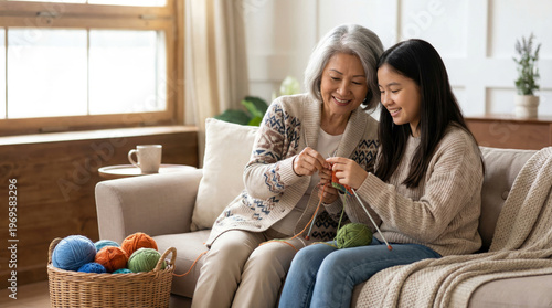 Asian Grandmother Teaching Granddaughter Knitting on Sofa in Modern Living Room