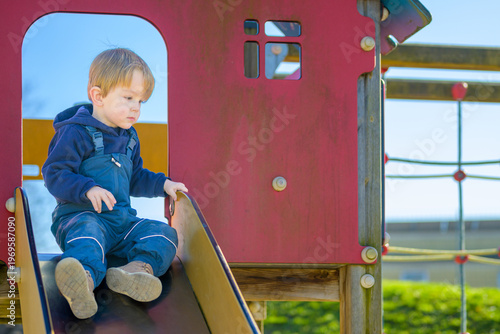 Toddler Sitting On Playground Slide