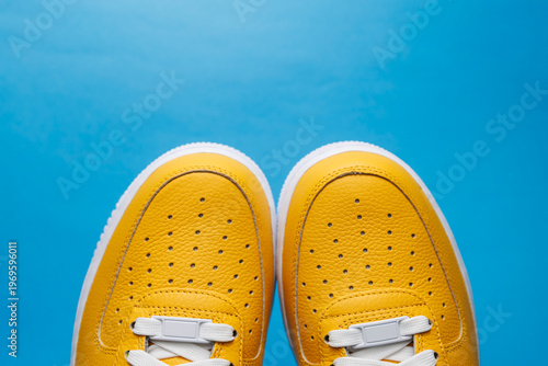 Paire de baskets jaunes sur fond bleu uni avec espace pour texte