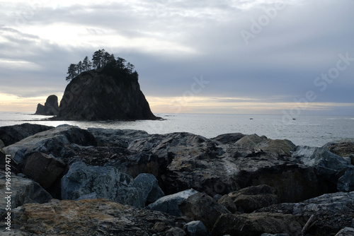 Big Rocks on Beach looking out to an Island with pine trees