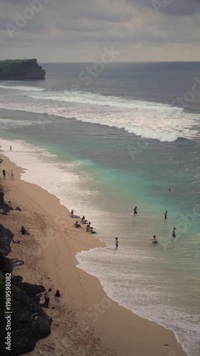 View of Tropical Beach with Tourists and Turquoise Waves from Cliff