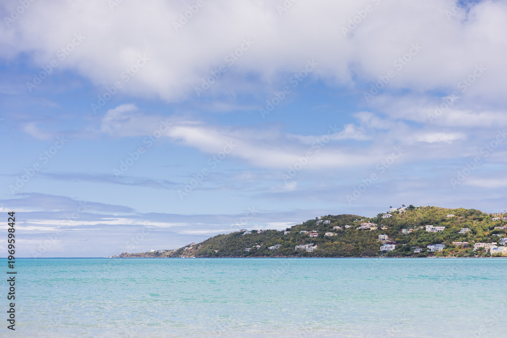 Naklejka premium Cloudy sky over calm Caribbean water with island coastline