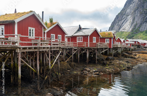 Traditional red fishing huts, known as rorbuer, standing on wooden stilts over the water in reine, a picturesque village in norway lofoten archipelago